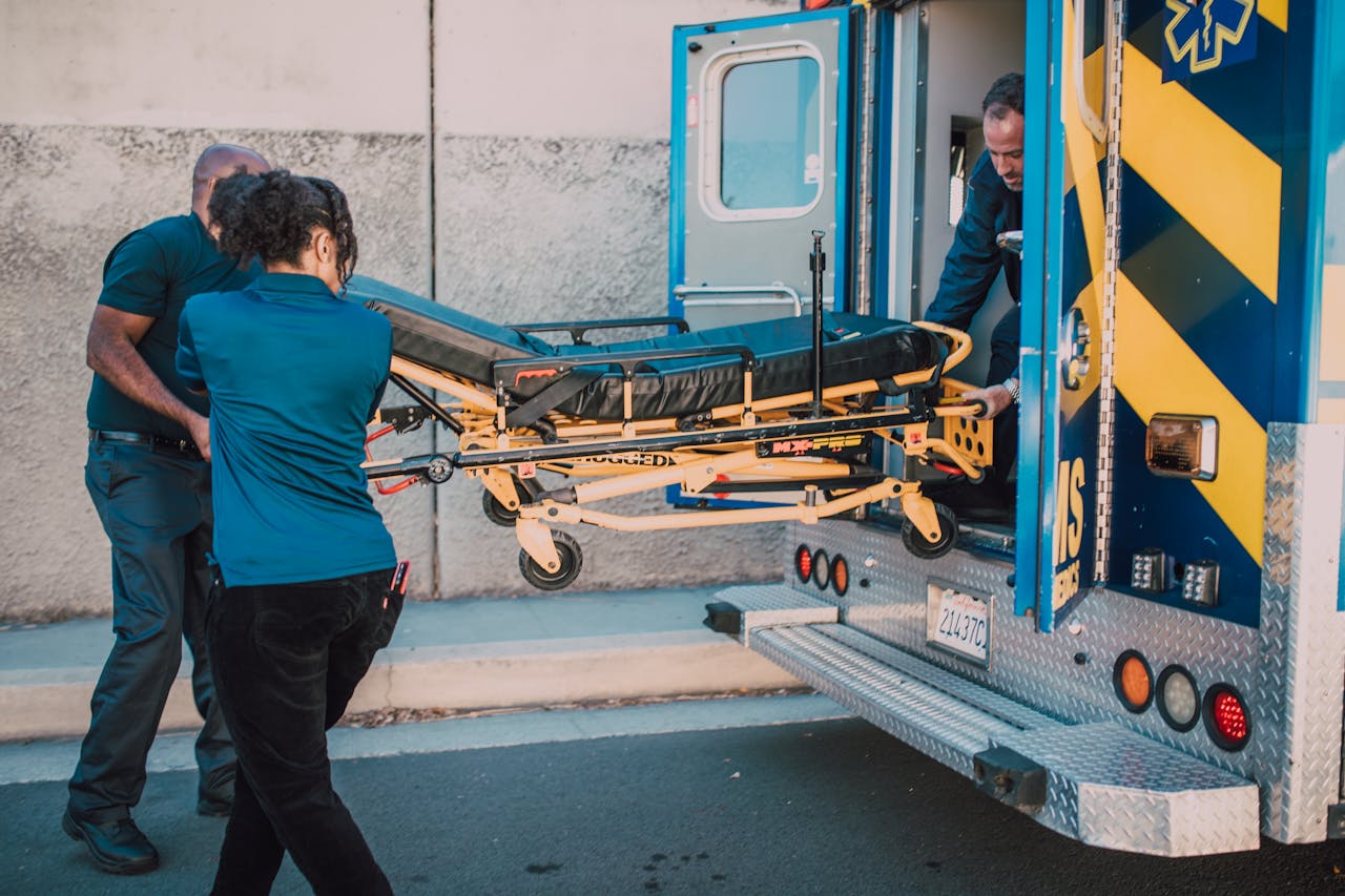Paramedic team efficiently loading a stretcher into an ambulance outdoors during daytime.